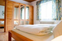 Gemütliches Zimmer mit Holzmöbeln, Fenstern und Blumenvorhängen im Haus Brigitte.